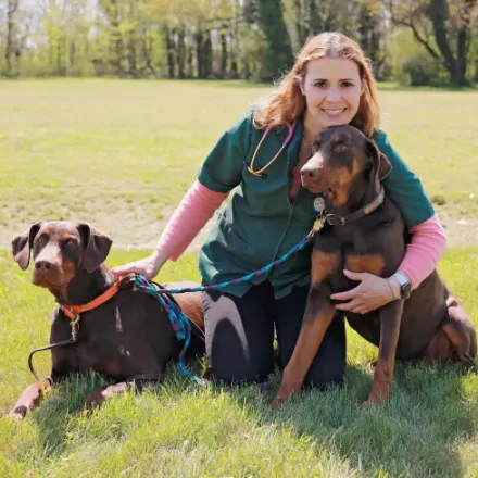 Dr. Adrienne B. Foster's stafff photo with her dobberman pincher next to her in the picture for Ferry Farm Animal Clinic photo op. 